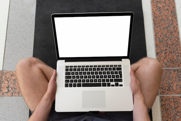 Photo man sitting on yoga map using laptop