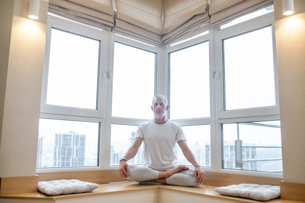 Man sitting in yoga pose at home