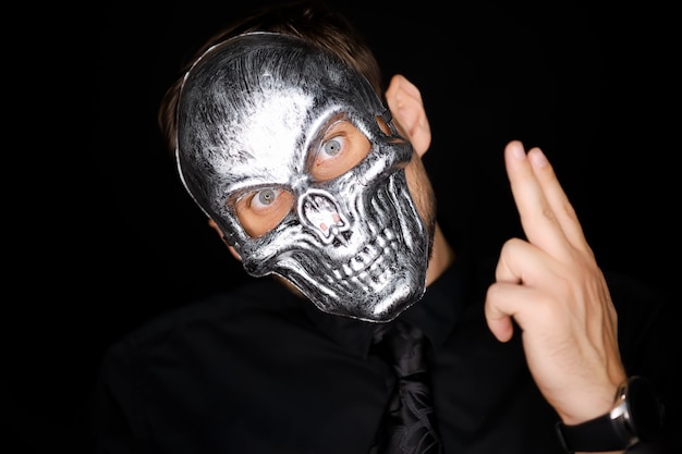 Photo a man in a skeleton mask shows a variety of gestures with his hand