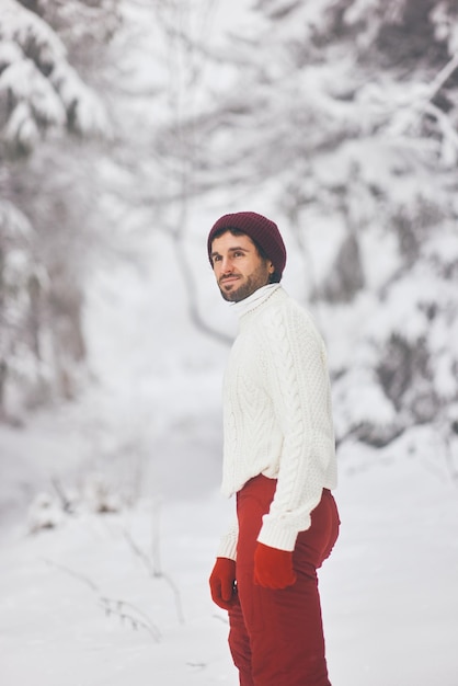 Man in ski suit and sweater in snowy forest during winter vacations outdoors