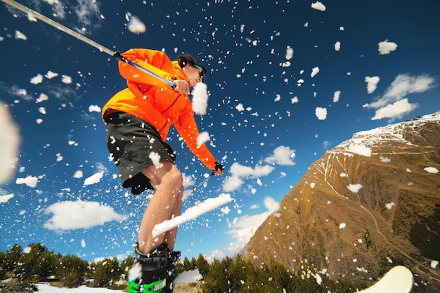 写真 春に山の背景にキッカーからジャンプした後飛行中の男スキーヤー