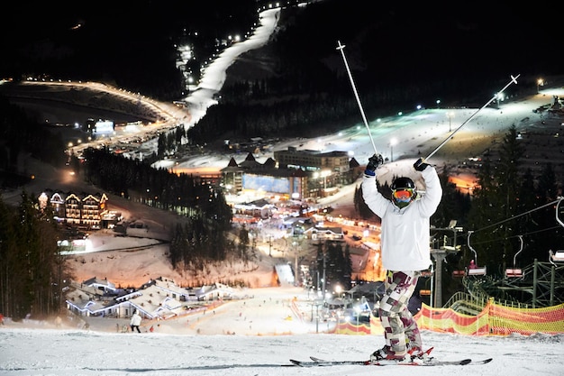 Man skier standing on snowy hill at night