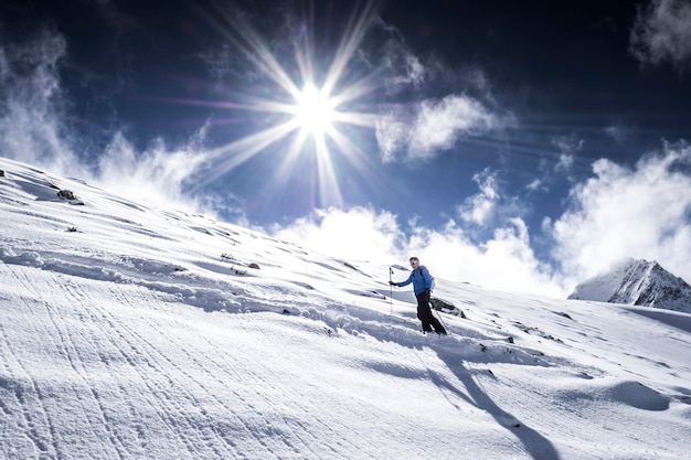 Man skiet op een besneeuwde berg tegen de lucht