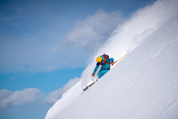 空を背景に雪を頂いた山でスキーをする男