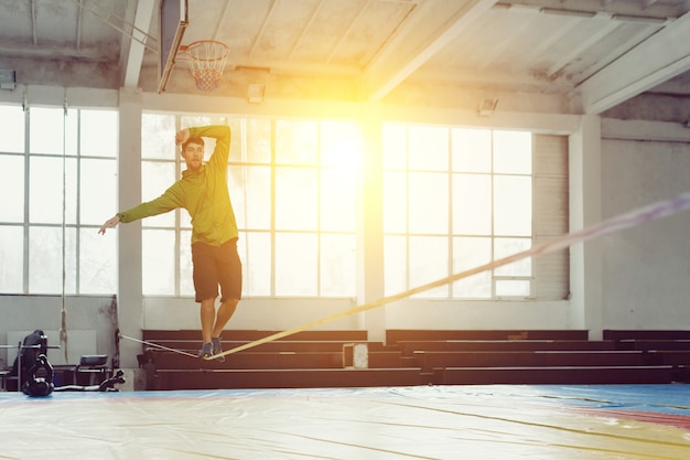 Man slacklining lopen en balanceren op een touw, slackline in een sporthal