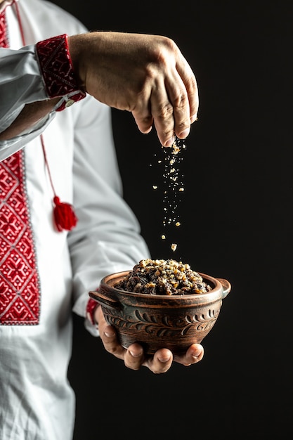 Man in slavic shirt holding bowl with traditional kutia