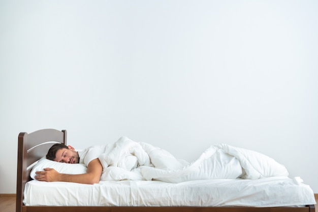 The man sleeping on the bed on the white background