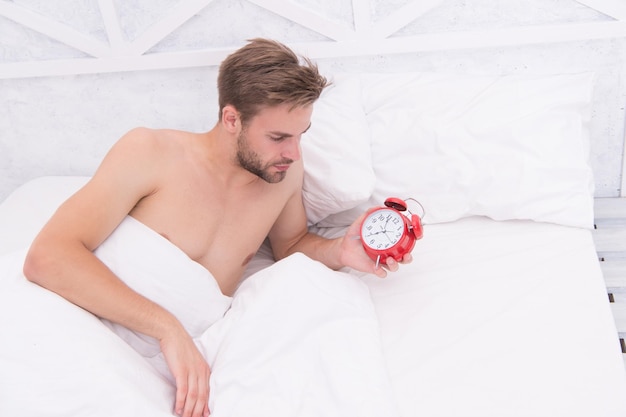 Man sleeping bed white bedclothes and red alarm clock time to\
wake up concept