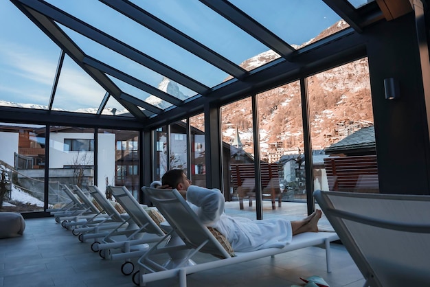 Man sleeping on deck chair by window at luxury hotel