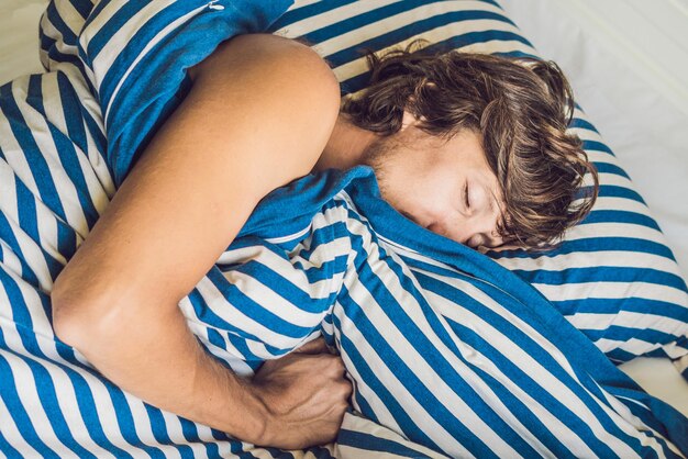 Man sleeping on his bed in bedroom at home