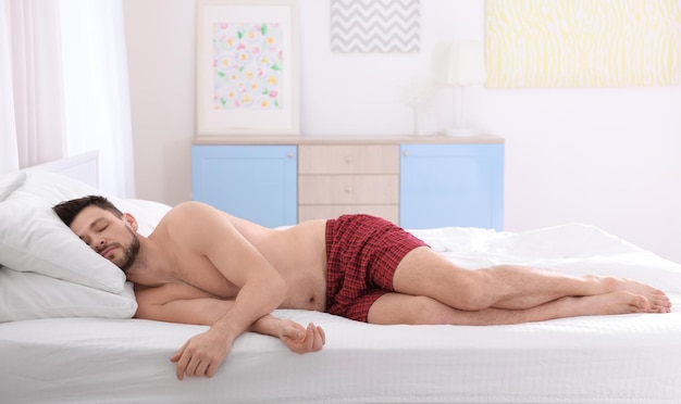 自宅で 2 つの枕で寝ている男 不適切な睡眠姿勢の概念