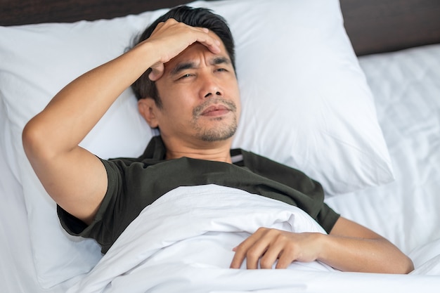 A man sleeping with a headache on his bed