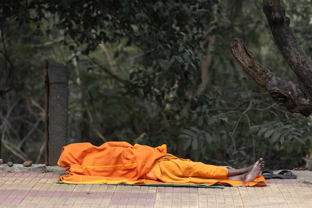 A man sleeps in front of a tree with a tree in the background