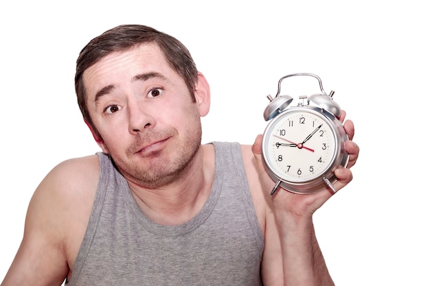 The man slept for work. A man in a raised hand holds an alarm clock. Funny facial expression. Isolated white background.