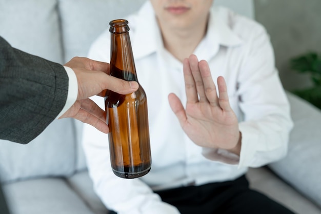 Foto l'uomo sorride e si rifiuta di dire no e evitare di bere un'alcol mostra la mano rifiutare e smettere di trattare l'alcolismo dipendenza dall'alcol smettere di bere alcol smettere di bere alcol rifiutare bottiglia di liquore non salutare