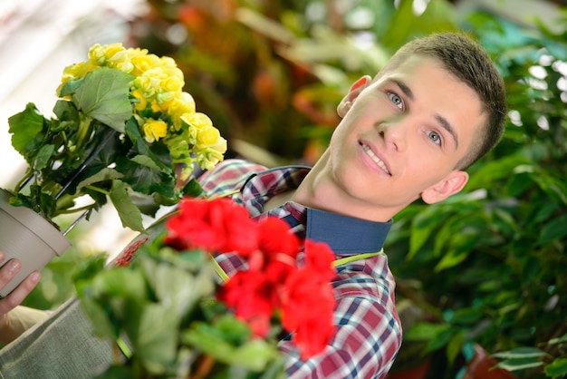 A man smiles and holds flowers in his hands.