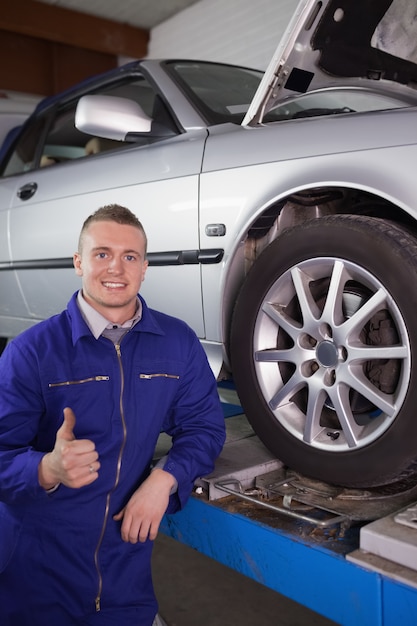 彼の親指で車の隣に笑っている男