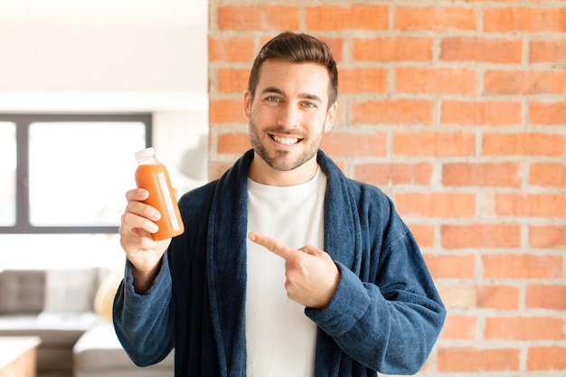 Man smiling cheerfully, feeling happy and pointing to the side and upwards, showing object in copy space