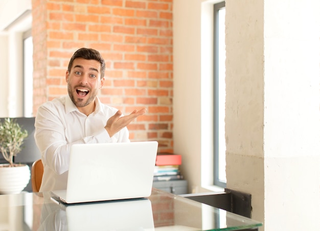 man smiling cheerfully, feeling happy and showing a concept in copy space with palm of hand