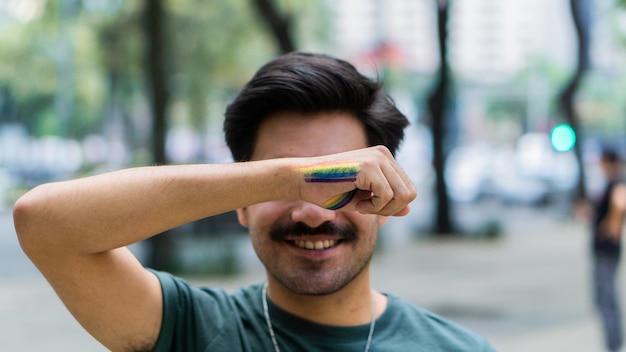 Man smiling and covering his eyes with his arm, gay pride.