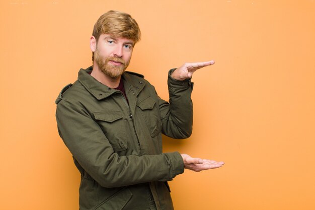 Man smiling, feeling happy, positive and satisfied, holding or showing object or concept on copy space