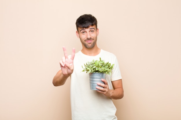 man smiling and looking happy, carefree and positive, gesturing victory or peace with one hand