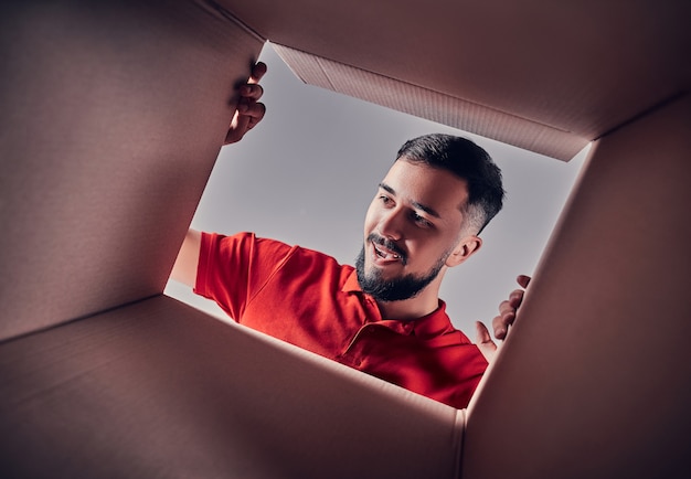 Man smiling, opening box and looking inside. The package, delivery, surprise, gift and lifestyle concept