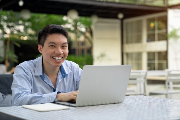 Photo a man smiling,using laptop.