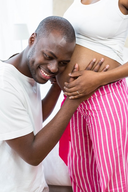 Man smiling while listening to pregnant womans stomach