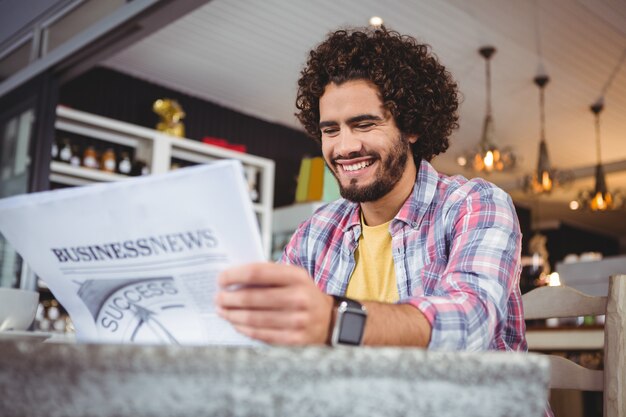 新聞を読みながら笑顔の男