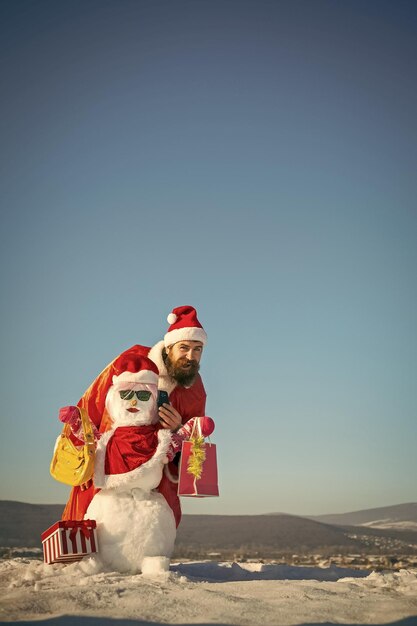 Man smiling with snowman and smartphone