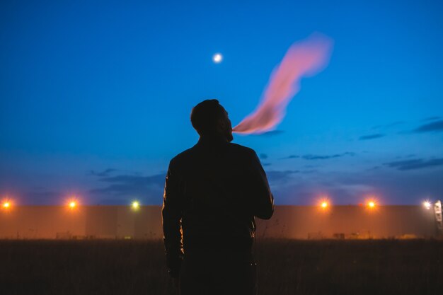 The man smoke cigarette near the building. evening night time