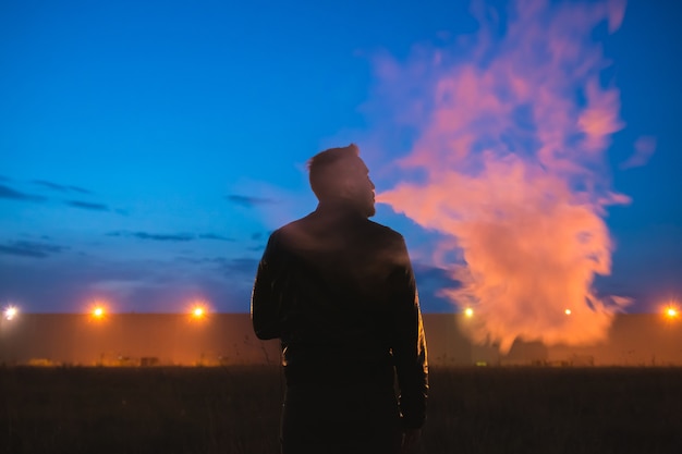 The man smoke cigarette near the building. evening night time