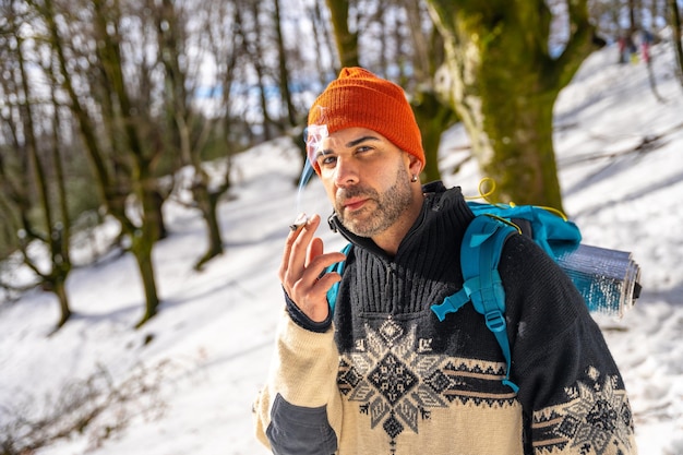 a man smoking a cigarette on a snowy hill in winter enjoying the cold smoking