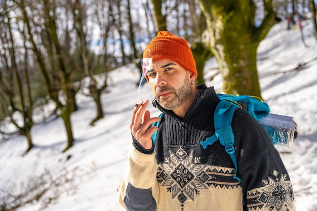 A man smoking a cigarette on a snowy hill in winter enjoying the cold smoking