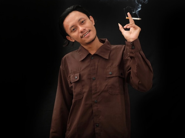 A man smoking a cigarette and wearing a brown shirt.