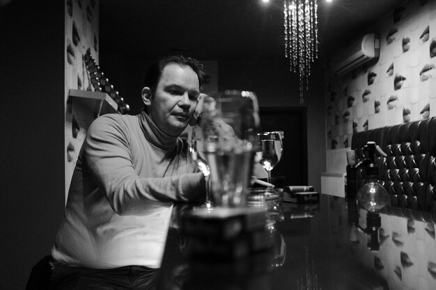 Photo man smoking cigarette while having drink at table in bar