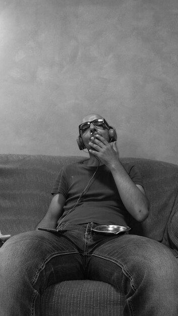 Photo man smoking cigarette while sitting on couch