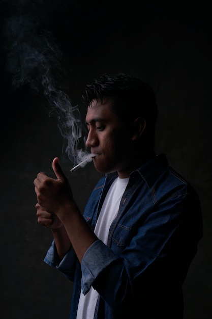 A man smoking a cigarette with a white shirt on.