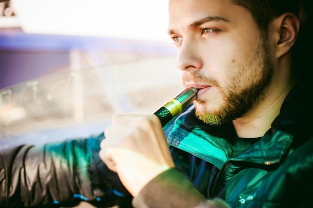 Фото Мужчина курит электронную сигарету.
