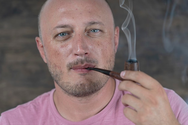 Мужчина курит трубку Портрет мужчины средних лет в помещении Зависимость от вредных привычек