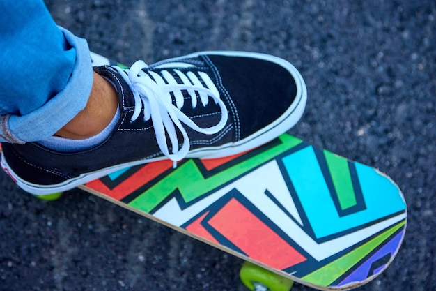 Man in sneakers and blue jeans stands on a children39s\
skateboard