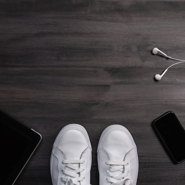 Man sneakers and gadgets on dark wood