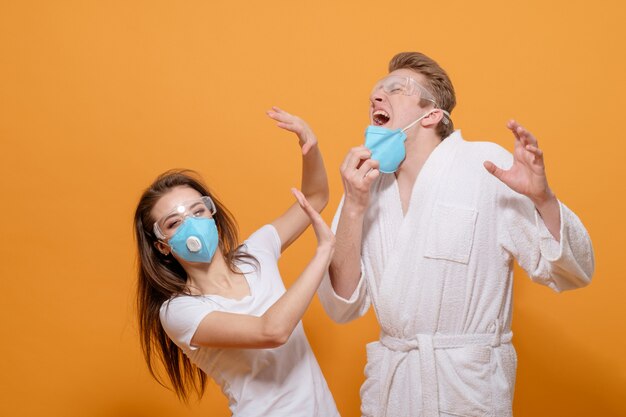 Man sneezes at woman  home quarantine coronavirus pandemic on  yellow orange 