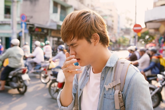 Man sneezing on street because bad air pollutionMan got nose allergy at outdoor