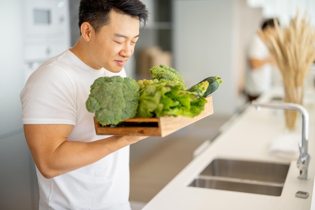 Мужчина нюхает свежие органические овощи в деревянном ящике