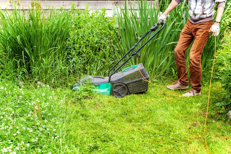Foto man snijden groen gras met grasmaaier in achtertuin tuinieren land levensstijl achtergrond prachtig uitzicht op vers groen gras gazon in zonlicht tuinlandschap in de lente of zomer