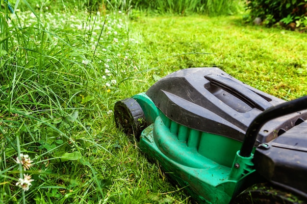 Man snijden groen gras met grasmaaier in de achtertuin. Tuinieren land levensstijl achtergrond