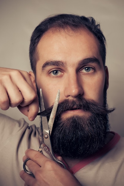 Foto man snijdt baard tegen een grijs achtergrondportret