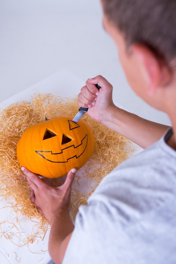 Foto man snijdt grote pompoen jack-o-lantern voor halloween